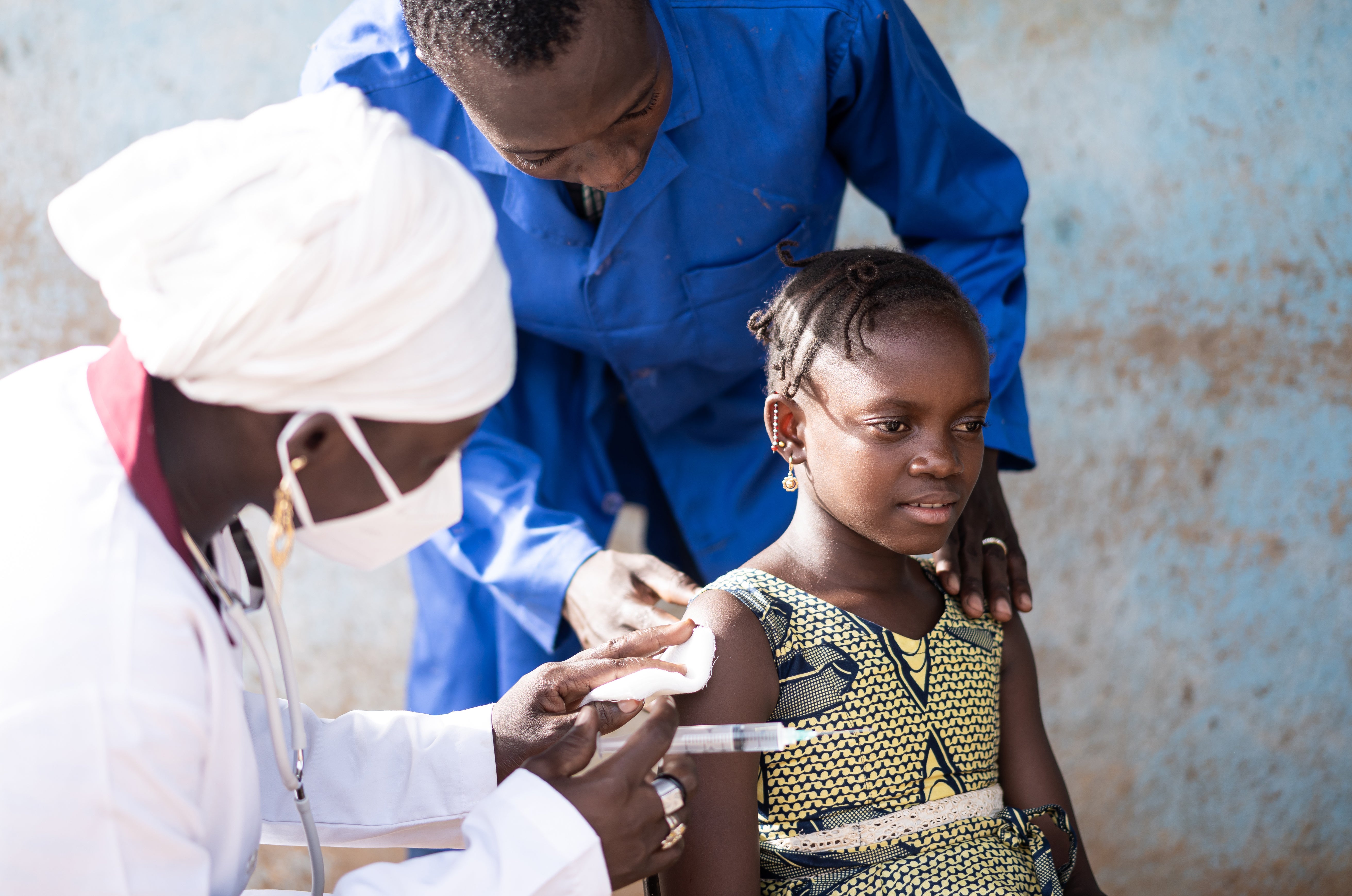 Doctors administrating an injection to a young girl in Africa