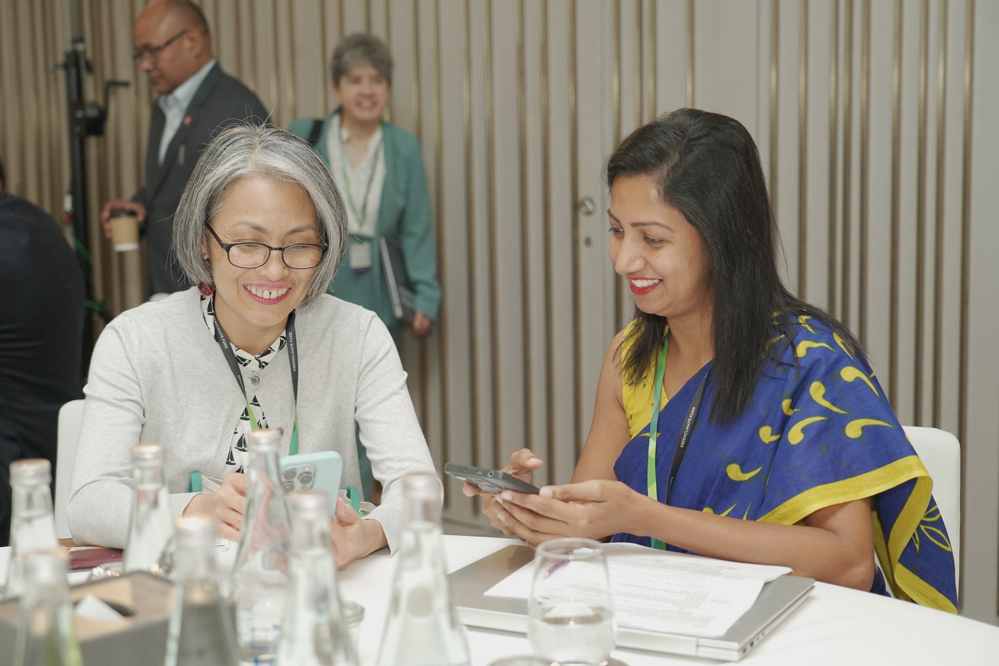 Female participants sitting at table with their phones at the Regional dialogue with East and South Asia