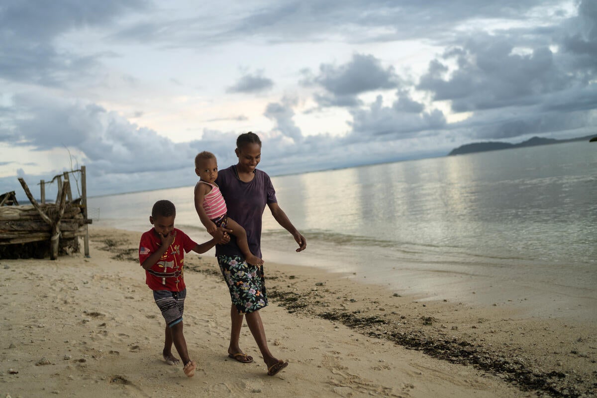 Tessa, 27, with her sons Jeffrian, 5, and Junior, 1, walking along the shoreline in Torba Province, Vanuatu.