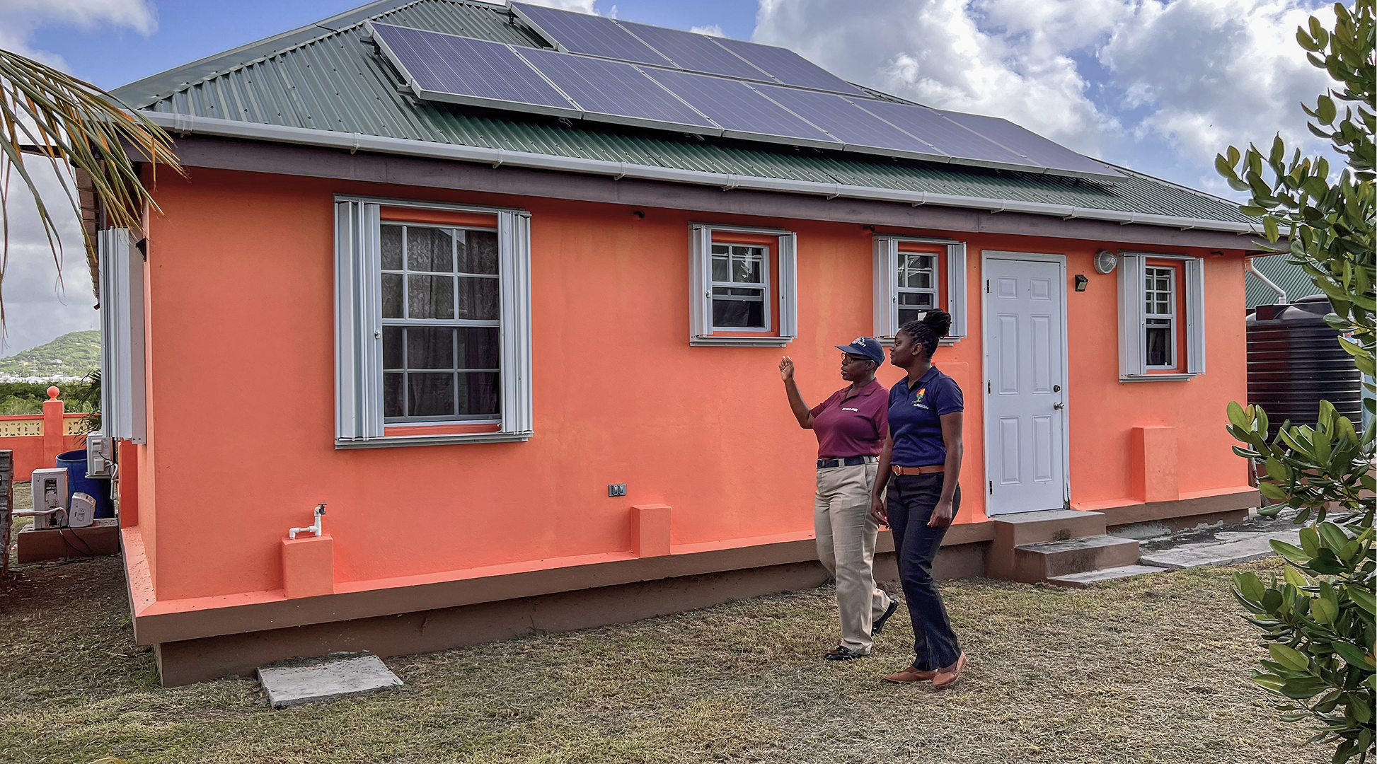 Firefighter Evette Henry shows the solar panels, water systems, and hurricane shutters that now protect her home— made possible through a financial scheme under a programme that strengthens building resilience and climate information systems. It also climate-proofs public and community buildings to withstand and recover from extreme events. Photo: GCF / Little Big Films