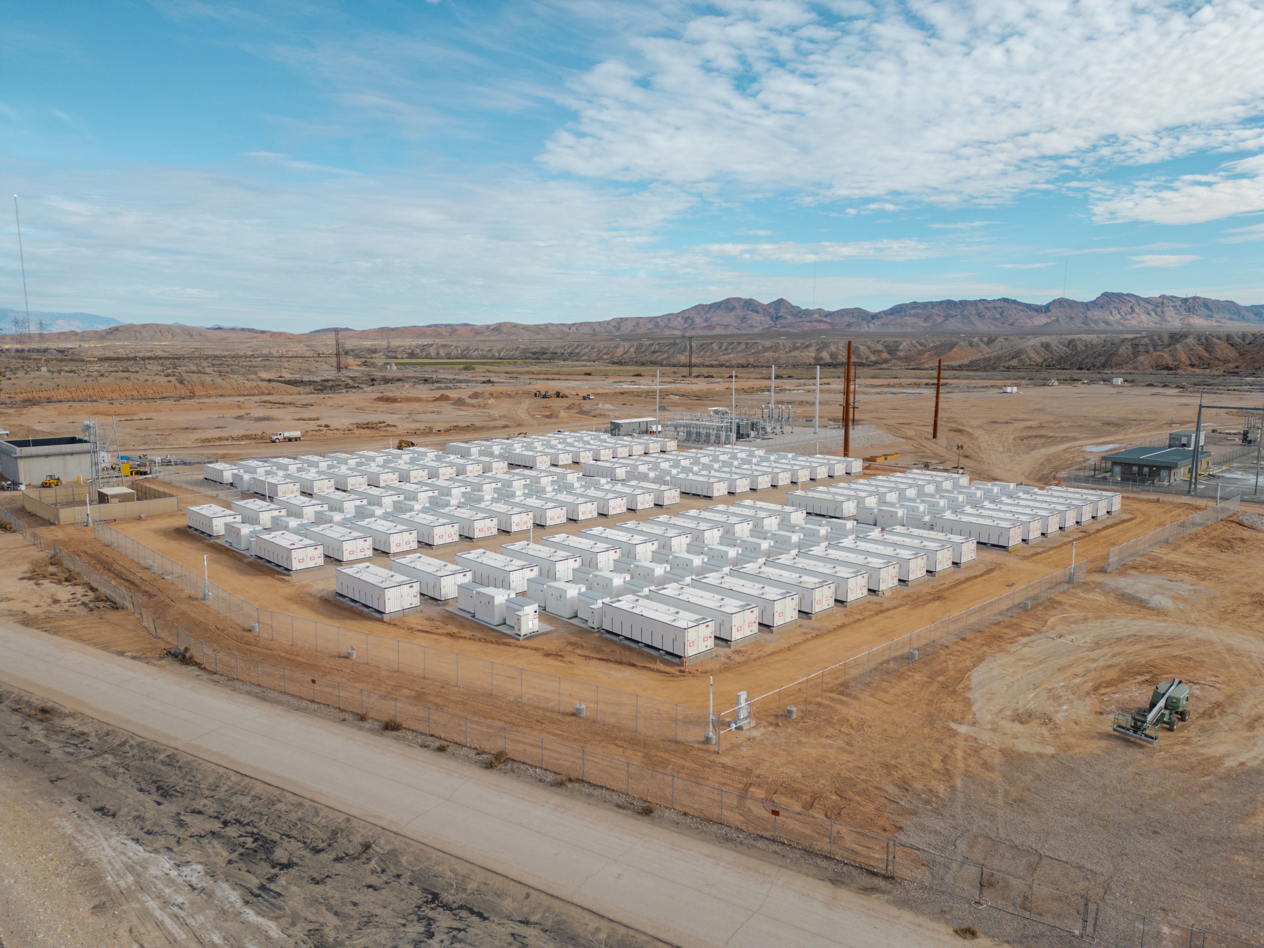 Large battery energy storage facility in a desert landscape surrounded by mountains.