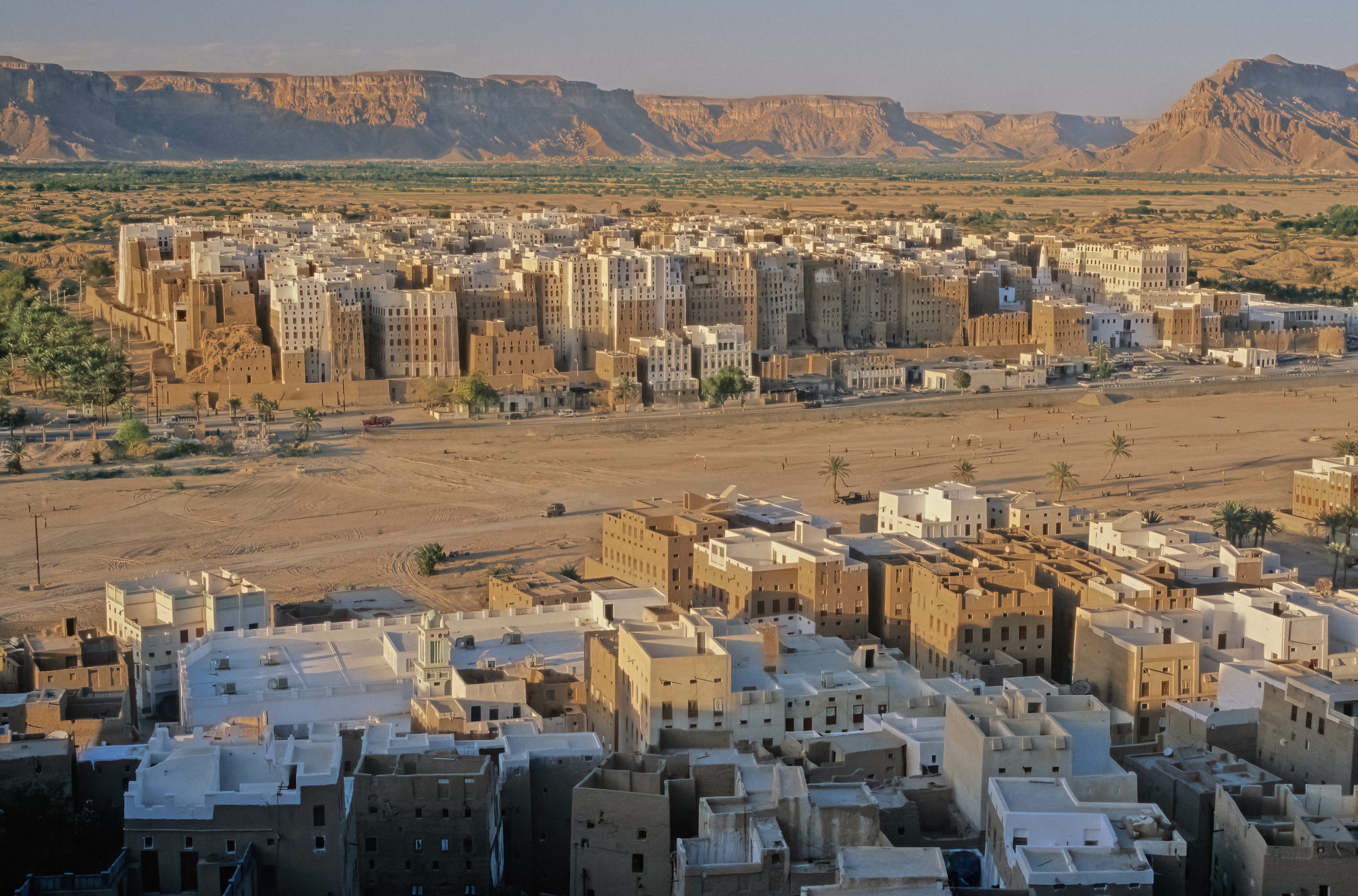 Dense cluster of traditional buildings in a desert valley surrounded by rugged mountains.