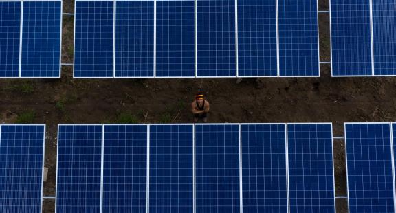 Gunter Yandari, President of the Association of Katinbaschi Artisanal Fishermen, stands between the 120 solar panels installed to power ice production. Photo: Profonanpe